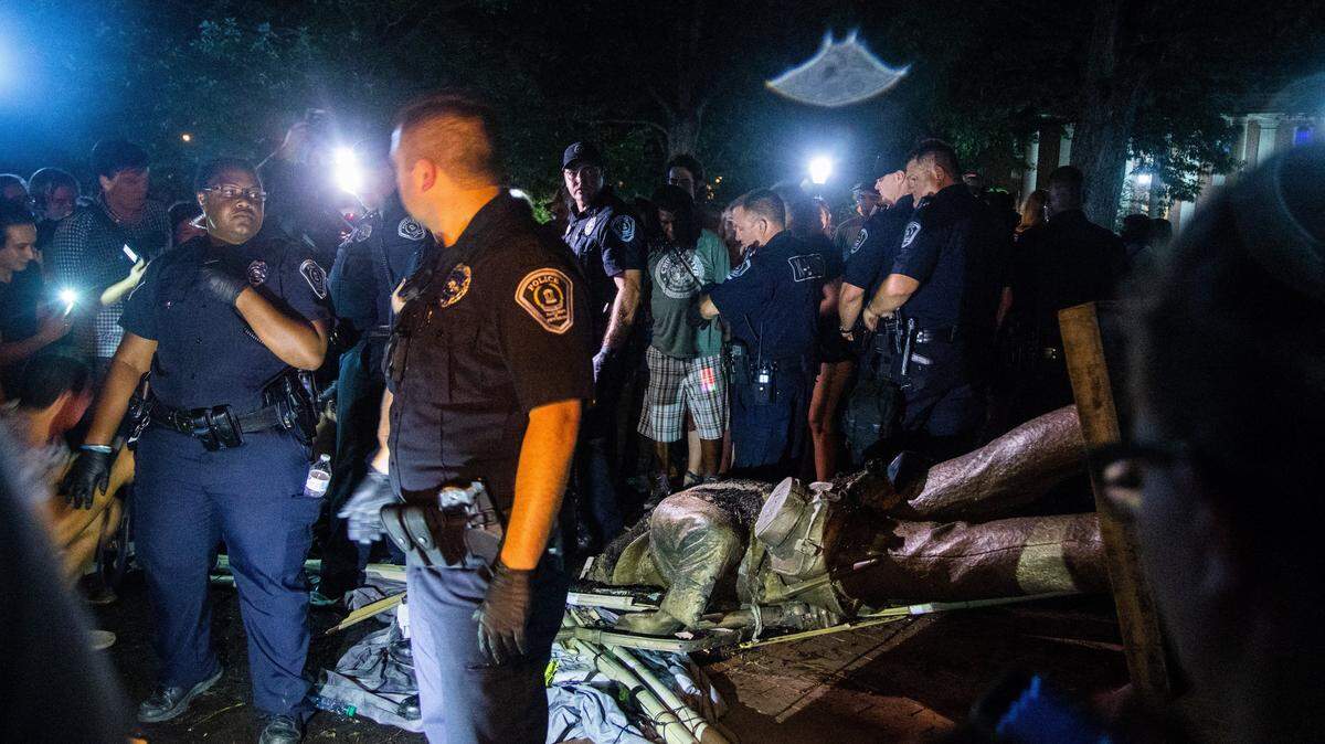Police surround the toppled remains of a Confederate statue known as Silent Sam Monday, August 20, 2018 at UNC-Chapel Hill. Demonstrators surrounded and obscured the statue with large banners before toppling it.