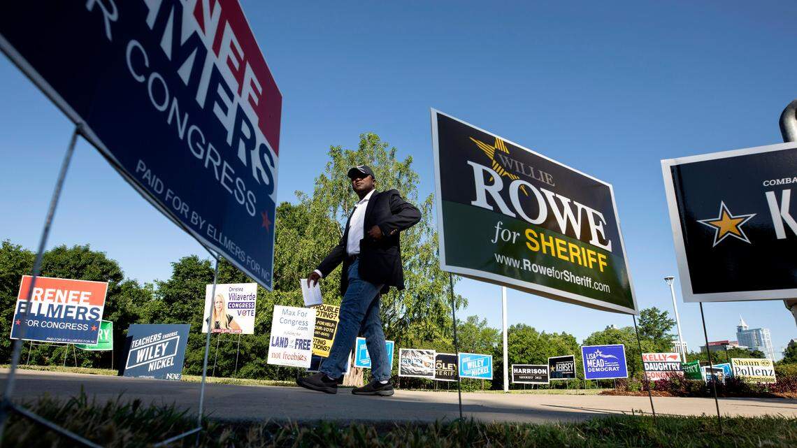 Nathan Click, a Democratic candidate for North Carolina’s 13th Congressional District, walks by campaign signs outside of the John Chavis Memorial Park Community Center polling site on Tuesday, May 17, 2022, in Raleigh, N.C.