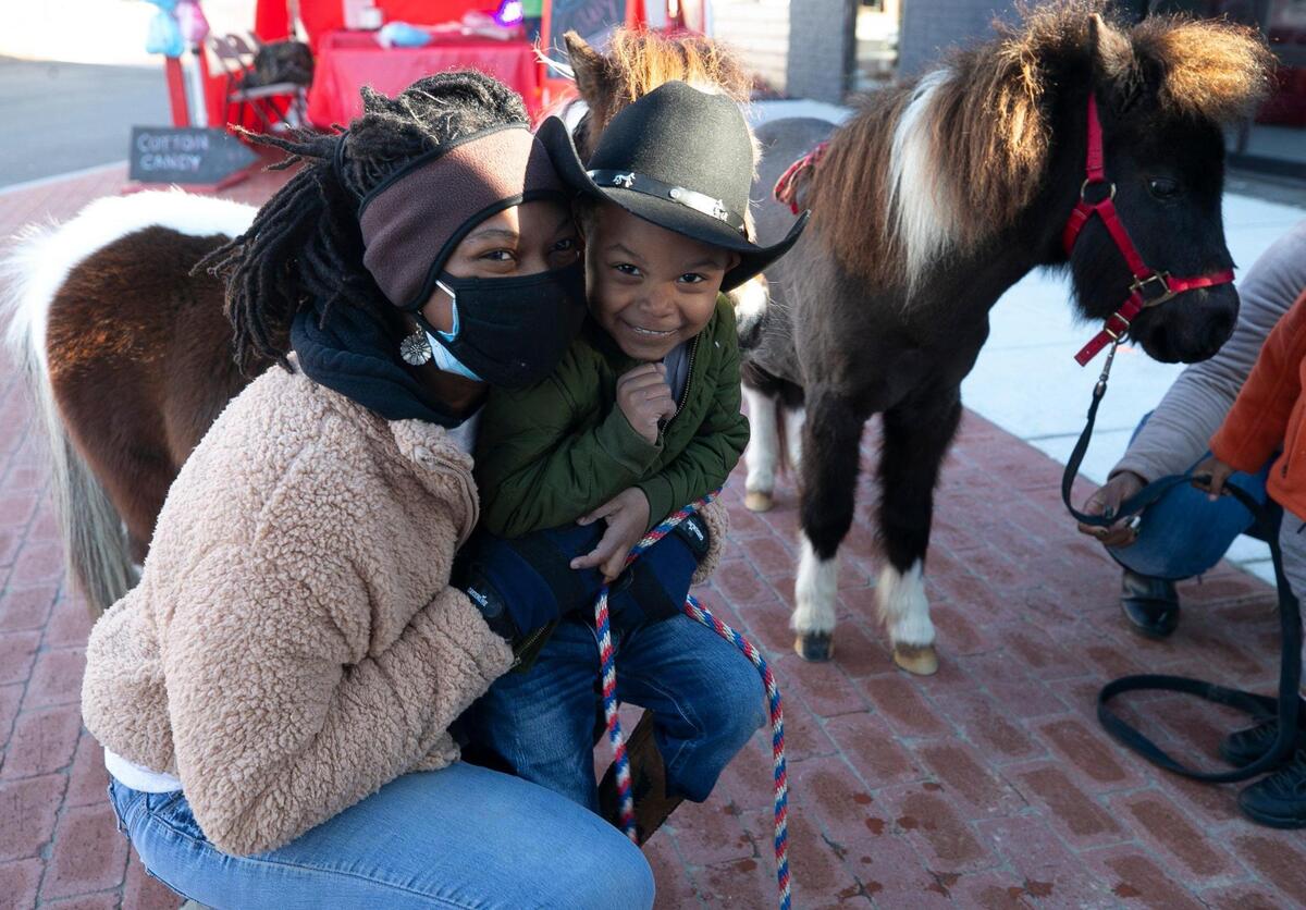 Caitlin Gooch, founder of Saddle Up and Read, poses for a photograph with three-year-old Sevyn Hodge of Raleigh, during a fundraiser and book drive on Saturday, December 19, 2020 in Wendell, N.C.