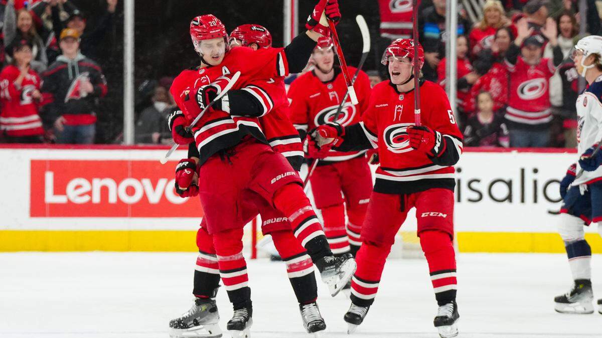 Carolina Hurricanes center Sebastian Aho (20) celebrates his goal with defenseman Dmitry Orlov (7) and defenseman Jalen Chatfield (5) and right wing Jackson Blake (53) against the Columbus Blue Jackets during the second period at Lenovo Center.