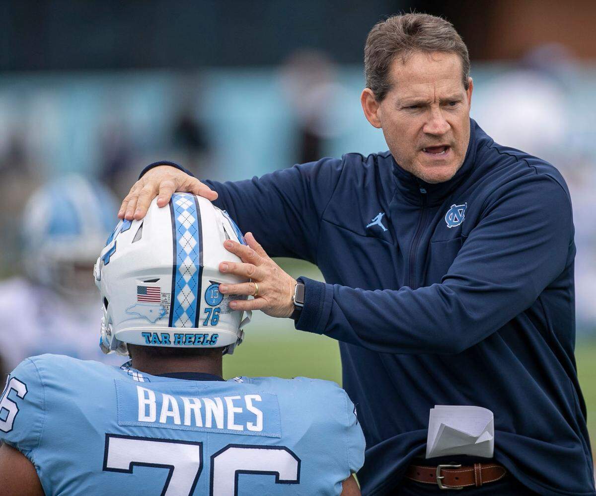 Gene Chizik, assistant head coach for defense, gives offensive linemen William Barnes (76) a pat on the head as the Tar Heels stretch prior to their spring football game on Saturday, April 9, 2022 at Kenan Stadium in Chapel Hill, N.C.