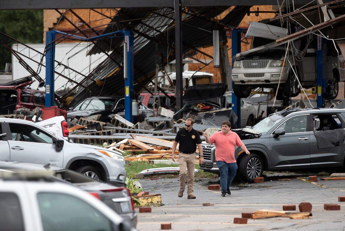 People walk through a parking lot off of North Wesleyan Boulevard where buildings sustained damage following a tornado in Rocky Mount, N.C. on Friday, Sept. 27, 2024.