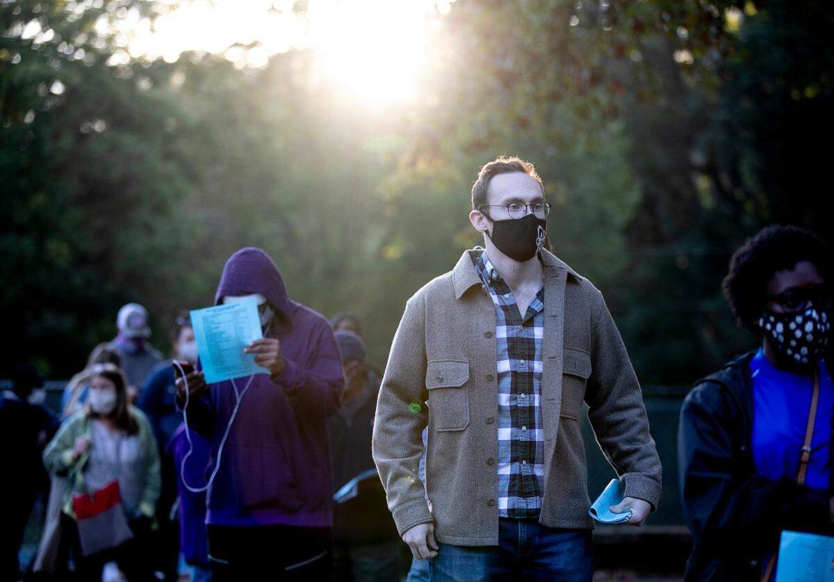 Nick Coco waits in line to vote as the sun rises over him on Thursday morning, October 15, 2020 in Raleigh, N.C. He was among the more than 300 people who were in line when the Roberts Park poll opened at 8 a.m..
