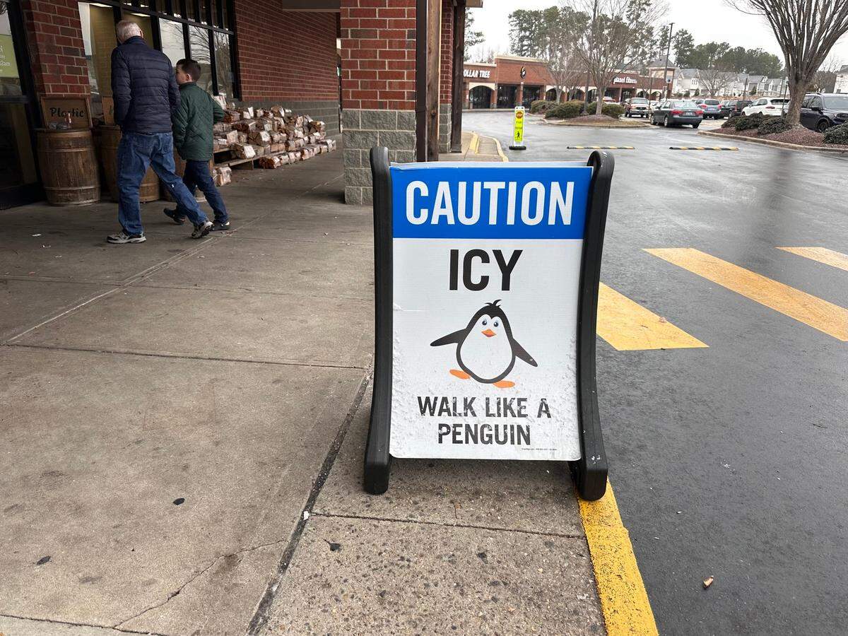 A sign outside Lowes’ Foods in Garner on Wednesday, Feb. 20, 2025 advises pedestrians to “walk like a penguin” in icy conditions.