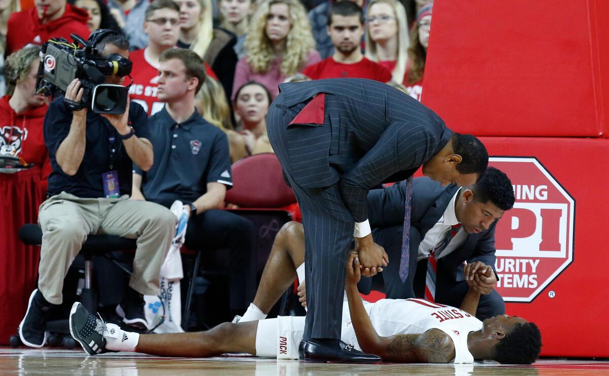 N.C. State head coach Kevin Keatts and trainer Drew Moore check on Markell Johnson (11) during the first half of N.C. State’s game against Pittsburgh at PNC Arena in Raleigh, N.C., Saturday, Jan. 12, 2019.