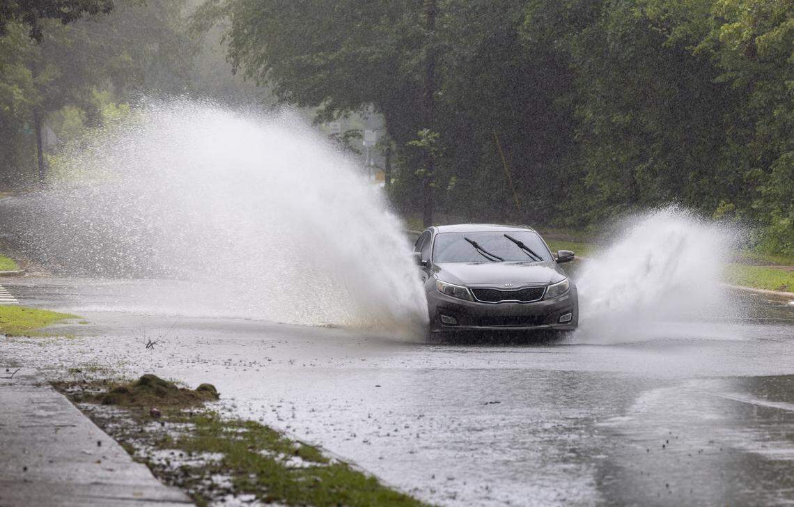 A vehicle moves through storm water that crosses State Street, flowing toward Walnut Creek, following an afternoon downpour on Wednesday, August 6, 2025 in Raleigh, N.C.