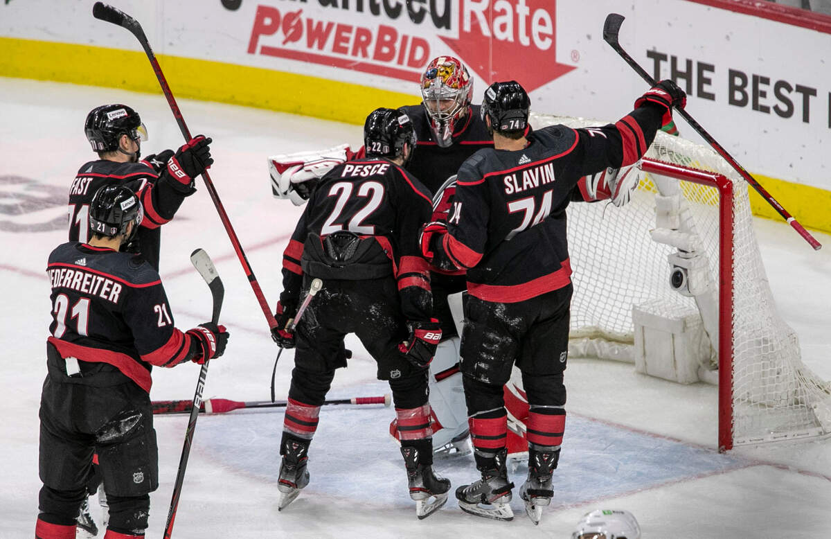 The Carolina Hurricanes players Brett Pesce (22) and Jaccob Slavin (74) celebrate their 3-2 victory over Boston with goalie Antii Raanta (32). after clinching the first round of their Stanley Cup series on Saturday, May 14, 2022 at PNC Arena in Raleigh, N.C.
