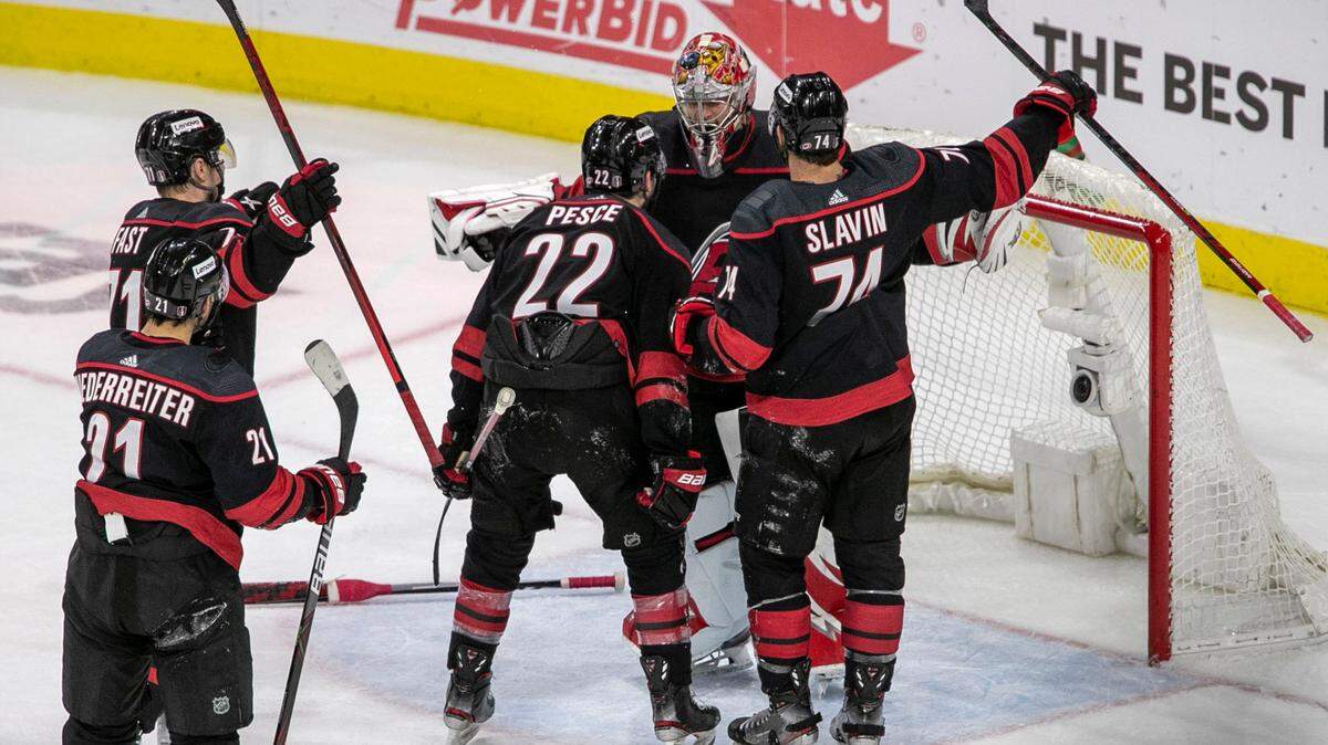 The Carolina Hurricanes players Brett Pesce (22) and Jaccob Slavin (74) celebrate their 3-2 victory over Boston with goalie Antii Raanta (32). after clinching the first round of their Stanley Cup series on Saturday, May 14, 2022 at PNC Arena in Raleigh, N.C.