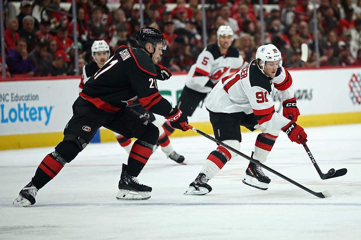 Dawson Mercer (91) of the New Jersey Devils controls the puck while defended by Alexander Nikishin of the Carolina Hurricanes during the first period of the game at Lenovo Center on October 09, 2025 in Raleigh, North Carolina.