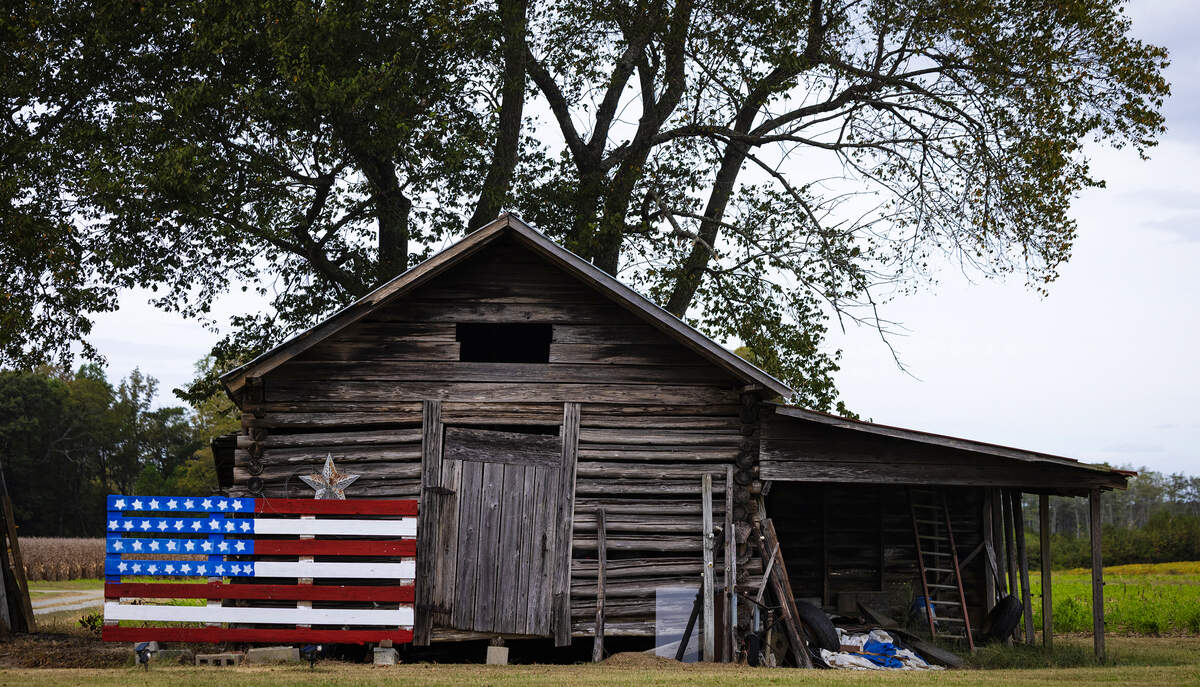 A homemade wooden version of the U.S. flag stands beside an old shed in Northampton County in northeastern N.C., Friday, October. 10, 2025.