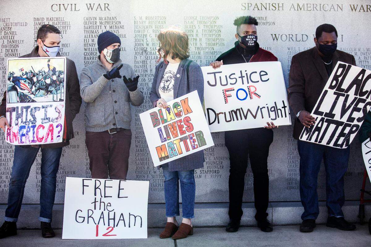 Supporters of Rev. Greg Drumwright and the racial justice movement in Graham, N.C. stand in front of a veteran’s memorial outside the J.B. Allen Jr. Criminal Courthouse as they wait for the start of a news conference on Dec. 2, 2020.