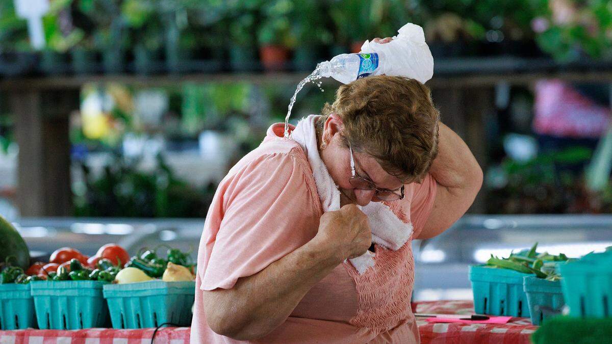 Barbara Johnson pours water over herself to stay cool while working at Johnson Family Produce at the State Farmers Market on Monday, June 23, 2025, in Raleigh, N.C.