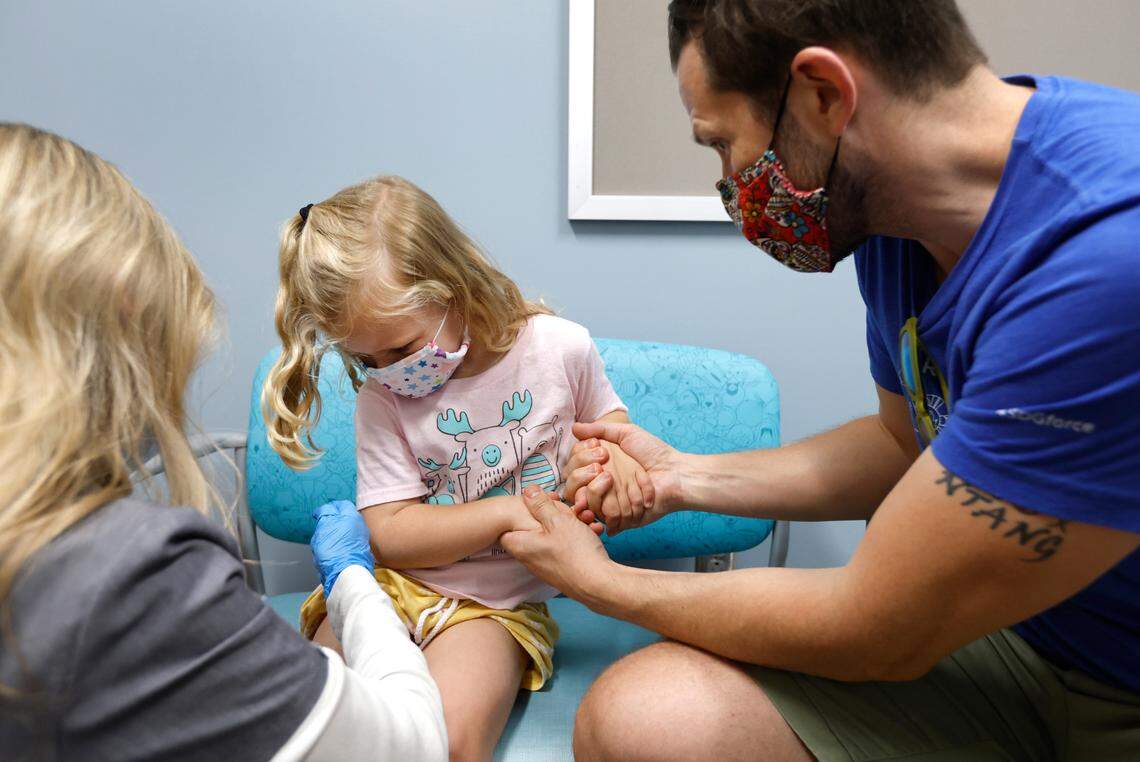 As her father Blair Reeves holds her hands, Penny Reeves, 4, of Pittsboro looks at where she just received a Moderna COVID-19 vaccine from Lynell Batchelor, RN, at UNC Family Medicine & Pediatrics at Panther Creek in Cary, N.C., on Friday, June 24, 2022.