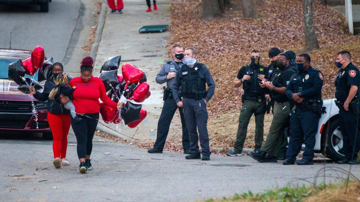 Mourners walk past law enforcement officers prior to a balloon release Thursday, Dec. 16, 2021 in Durham at the site of a Dec. 13, 2021, shooting that left two teenagers dead and four other children injured.