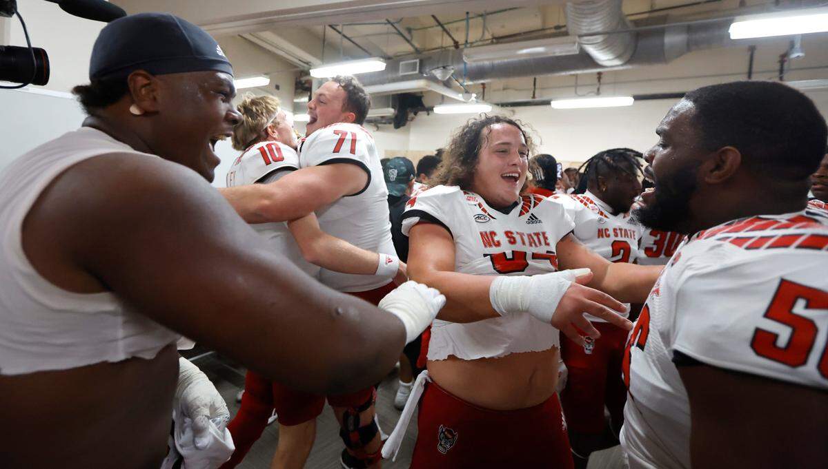 From left, N.C. State’s Timothy McKay (52), Ben Finley (10), Thornton Gentry (71), Dylan McMahon (54) and guard Bryson Speas (56) celebrate in the locker room after N.C. State’s 30-27 overtime victory over UNC at Kenan Stadium in Chapel Hill, N.C., Friday, Nov. 25, 2022.