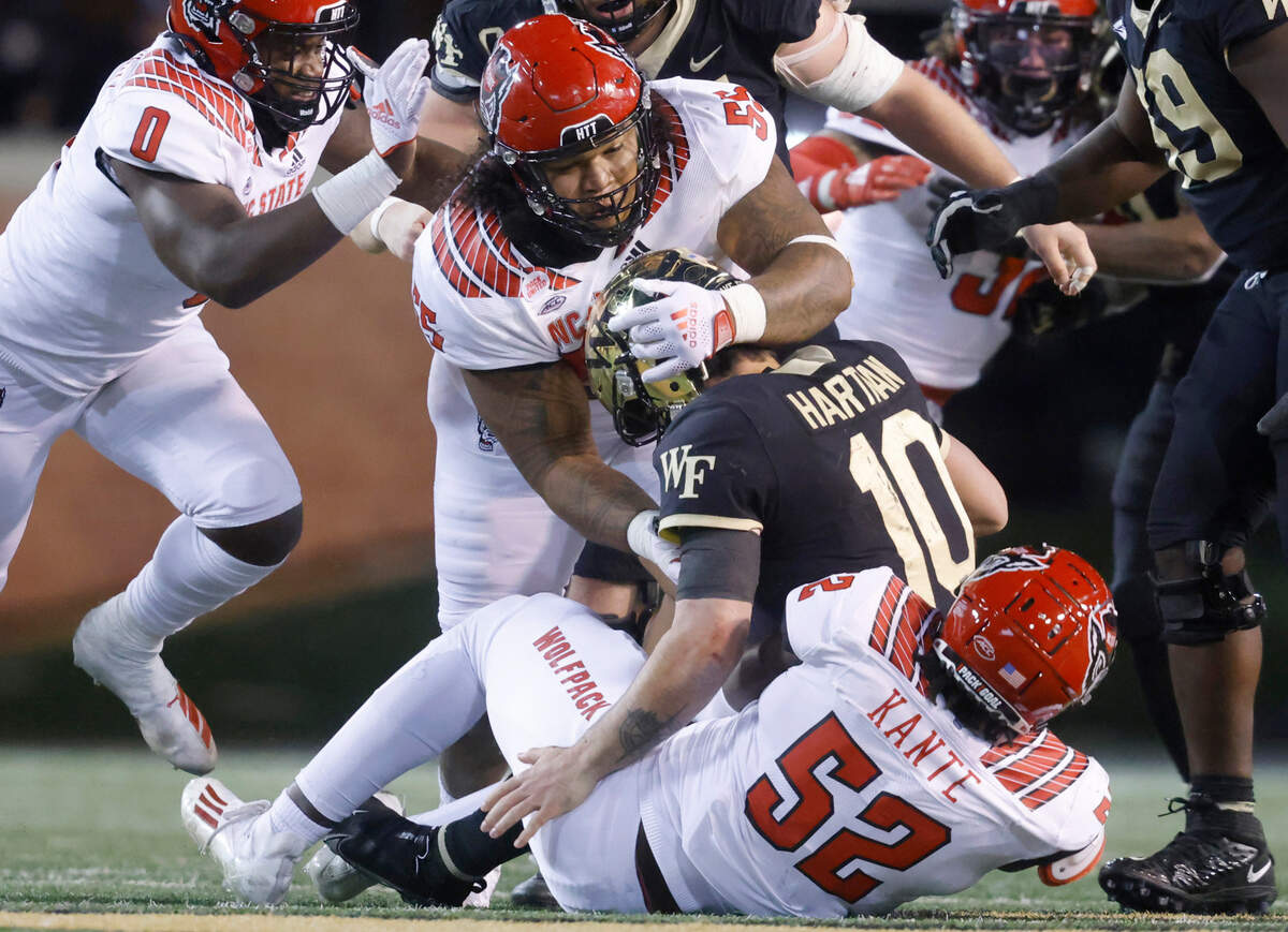 N.C. State’s Joshua Harris (55) and Ibrahim Kante (52) sack Wake Forest quarterback Sam Hartman during the Wolfpack’s game against the Demon Deacons at Truist Field in Winston-Salem, N.C., Saturday, November 13, 2021.