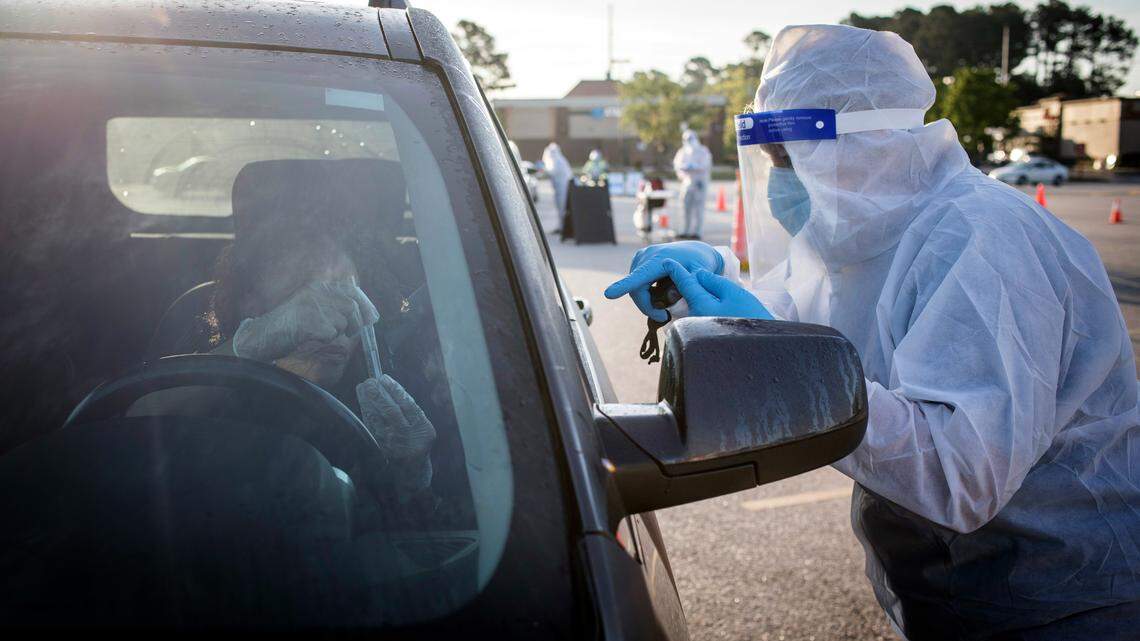 Walmart pharmacist Royanna Morris, right, instructs Brenda Haywood, who is talking to Morris on her cell phone while her window is closed, on how to administer a COVID-19 test in her vehicle at the Walmart on Ramsey Street in Fayetteville, N.C. on Friday, May 15, 2020. Pre-registered individuals who qualify can now receive COVID-19 tests, provided by eTrueNorth, in the Walmart parking lot from 7a.m. to 9a.m. on Mondays, Wednesdays and Fridays.