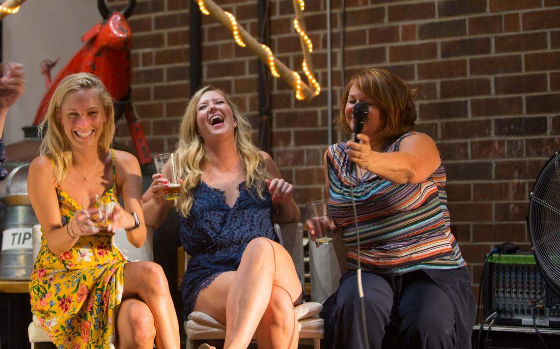 Kate Lundy, Bridger Davenport, and Debbie Kennedy, contestants on the comedy dating show Love at First Pint, share a laugh on stage at Fullsteam Brewery Wednesday, July 11, 2018.
