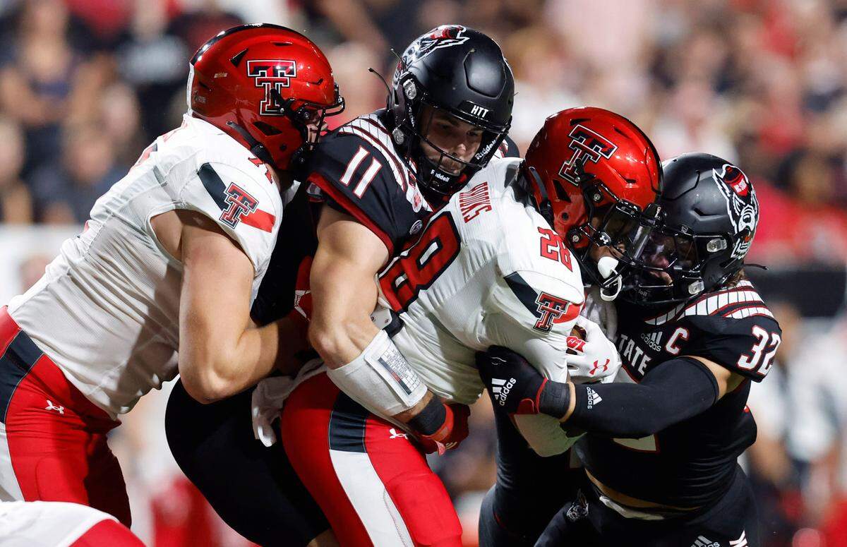 N.C. State linebacker Payton Wilson (11) and N.C. State linebacker Drake Thomas (32) tackle Texas Tech running back Tahj Brooks (28) during the first half of N.C. State’s game against Texas Tech at Carter-Finley Stadium in Raleigh, N.C., Saturday, Sept. 17, 2022. Texas Tech offensive lineman Monroe Mills (71) tries to stop Wilson.