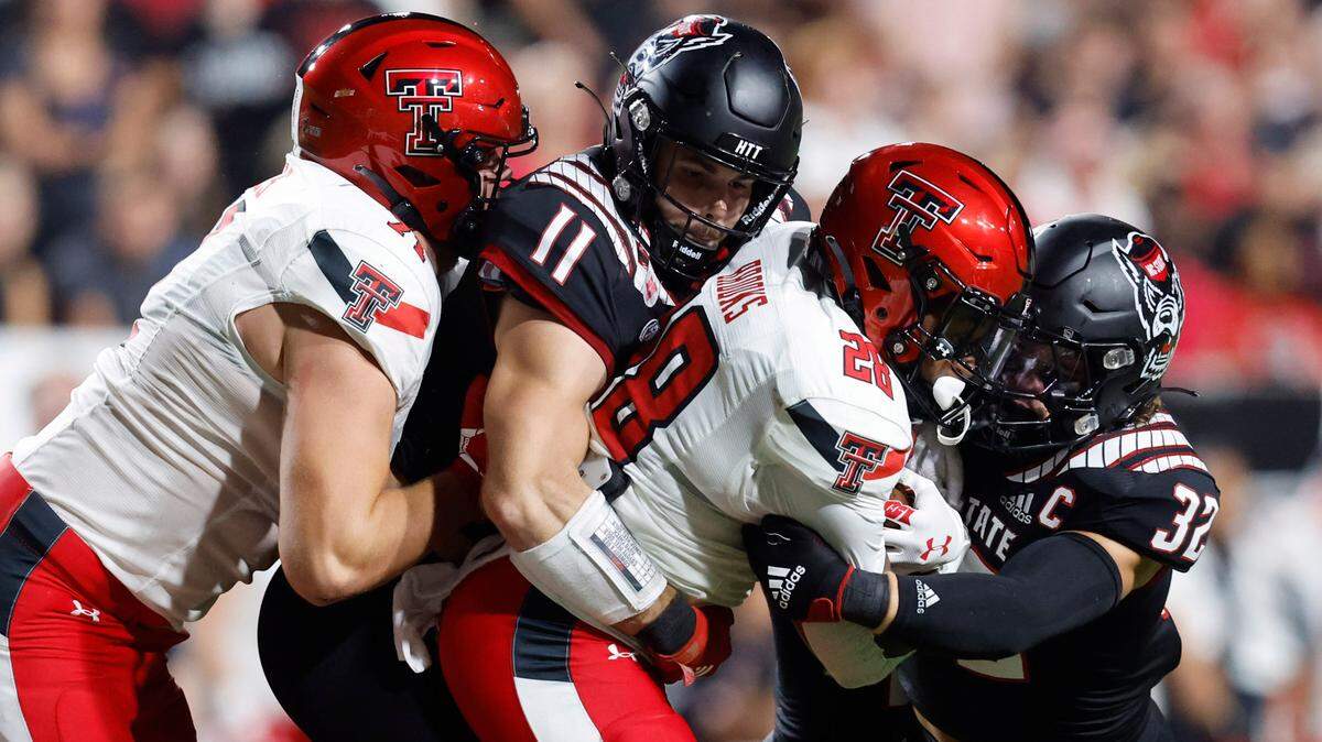 N.C. State linebacker Payton Wilson (11) and N.C. State linebacker Drake Thomas (32) tackle Texas Tech running back Tahj Brooks (28) during the first half of N.C. State’s game against Texas Tech at Carter-Finley Stadium in Raleigh, N.C., Saturday, Sept. 17, 2022. Texas Tech offensive lineman Monroe Mills (71) tries to stop Wilson.