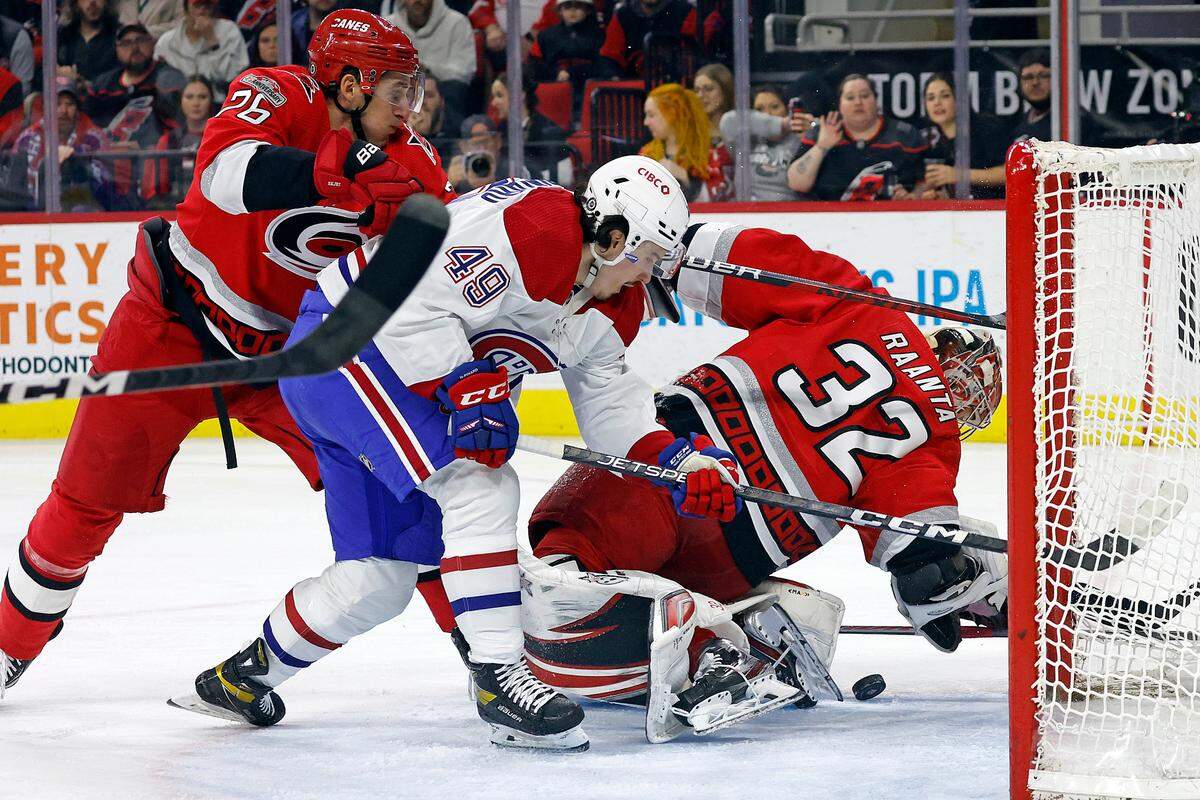 Carolina Hurricanes goaltender Antti Raanta (32) reaches behind his back to stop the puck as Hurricanes’ Brady Skjei (76) ties up Montreal Canadiens’ Rafael Harvey-Pinard (49) during the first period of an NHL hockey game in Raleigh, N.C., Thursday, Feb. 16, 2023. (AP Photo/Karl B DeBlaker)