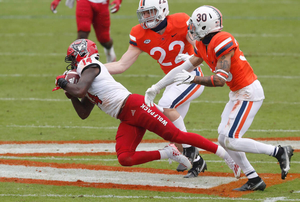 N.C. State wide receiver Porter Rooks (14) makes the reception as Virginia’s Rob Snyder (22) and D’Angelo Amos (30) defend during the first half of N.C. State’s game against Virginia at Scott Stadium in Charlottesville, Va., Saturday, Oct. 10, 2020.