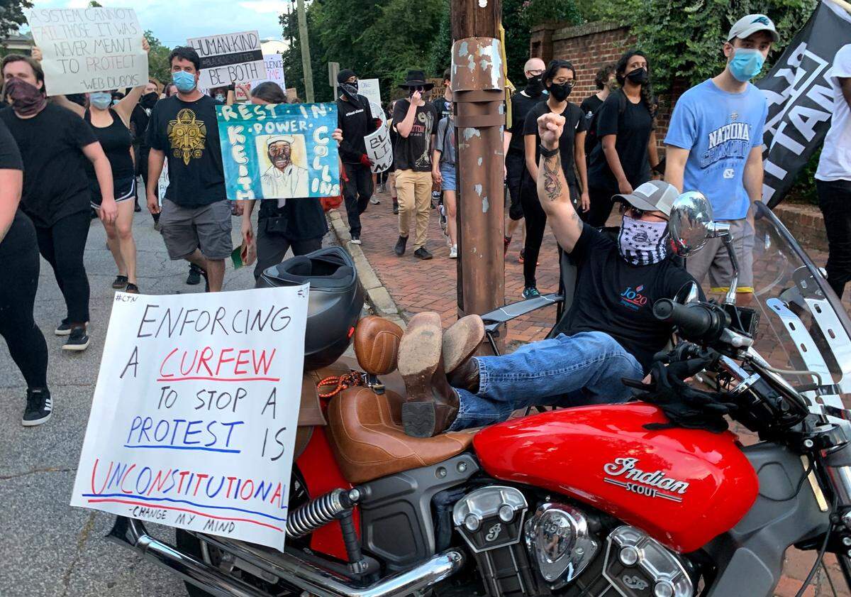 A man reclines on his motorcycle as demonstrators march around the Executive Mansion in protest against systemic racism in downtown Raleigh Friday, Aug. 28, 2020 after the police shooting of Jacob Blake in Kenosha, WI.