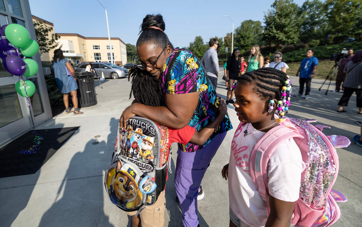 Jazzmine Farr gives her son Urijah Smith a hug before he and Farr’s daughter Maliyah Smith, right, head into Green Magnet Elementary School on their first day Tuesday, August 27, 2024. Urijah is a first grader and Maliyah is a second grader.