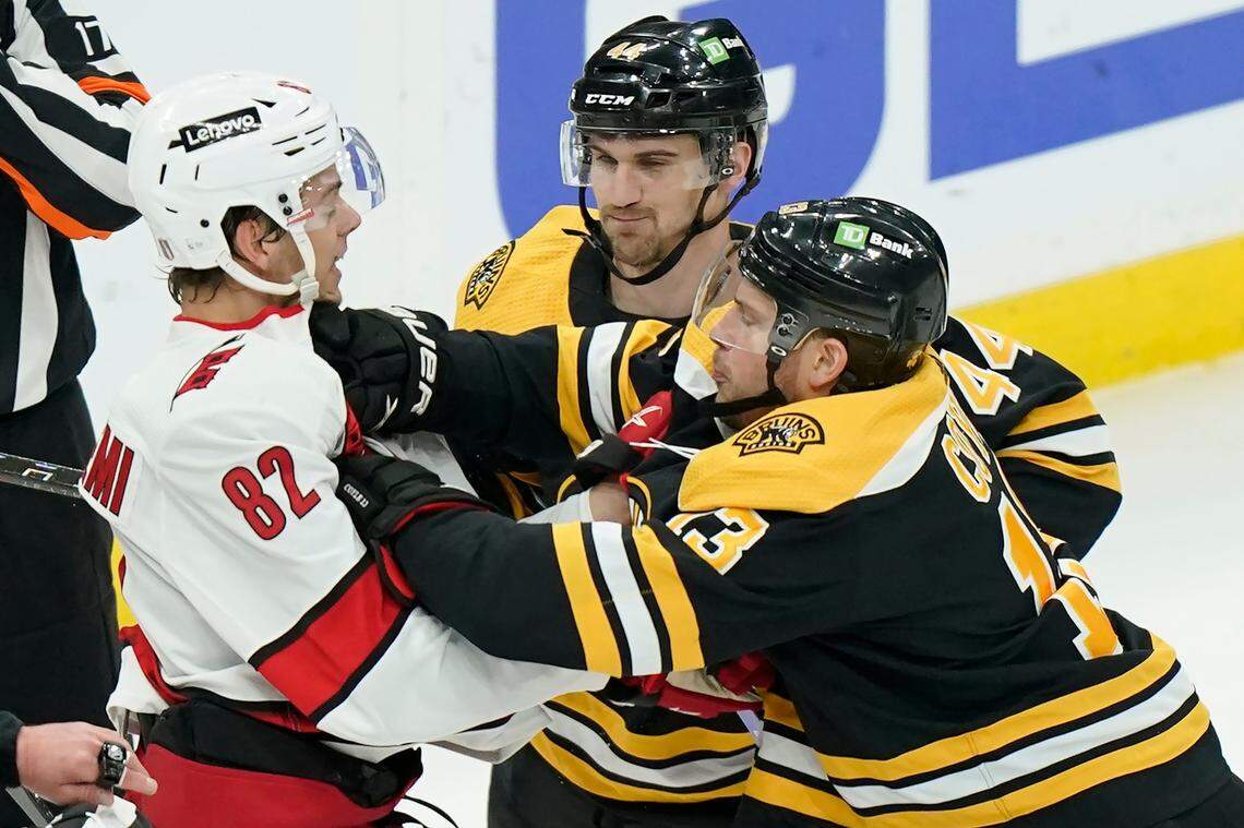 Carolina Hurricanes’ Jesperi Kotkaniemi, of Finland (82) grapples with Boston Bruins’ Charlie Coyle (13), right, as Bruins’ Josh Brown (44), behind, looks on in the first period of Game 4 of an NHL hockey Stanley Cup first-round playoff series, Sunday, May 8, 2022, in Boston. (AP Photo/Steven Senne)