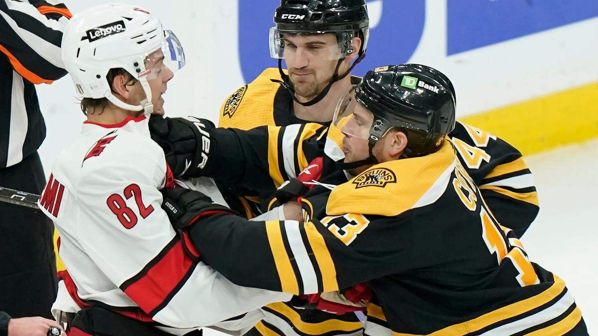 Carolina Hurricanes’ Jesperi Kotkaniemi, of Finland (82) grapples with Boston Bruins’ Charlie Coyle (13), right, as Bruins’ Josh Brown (44), behind, looks on in the first period of Game 4 of an NHL hockey Stanley Cup first-round playoff series, Sunday, May 8, 2022, in Boston. (AP Photo/Steven Senne)