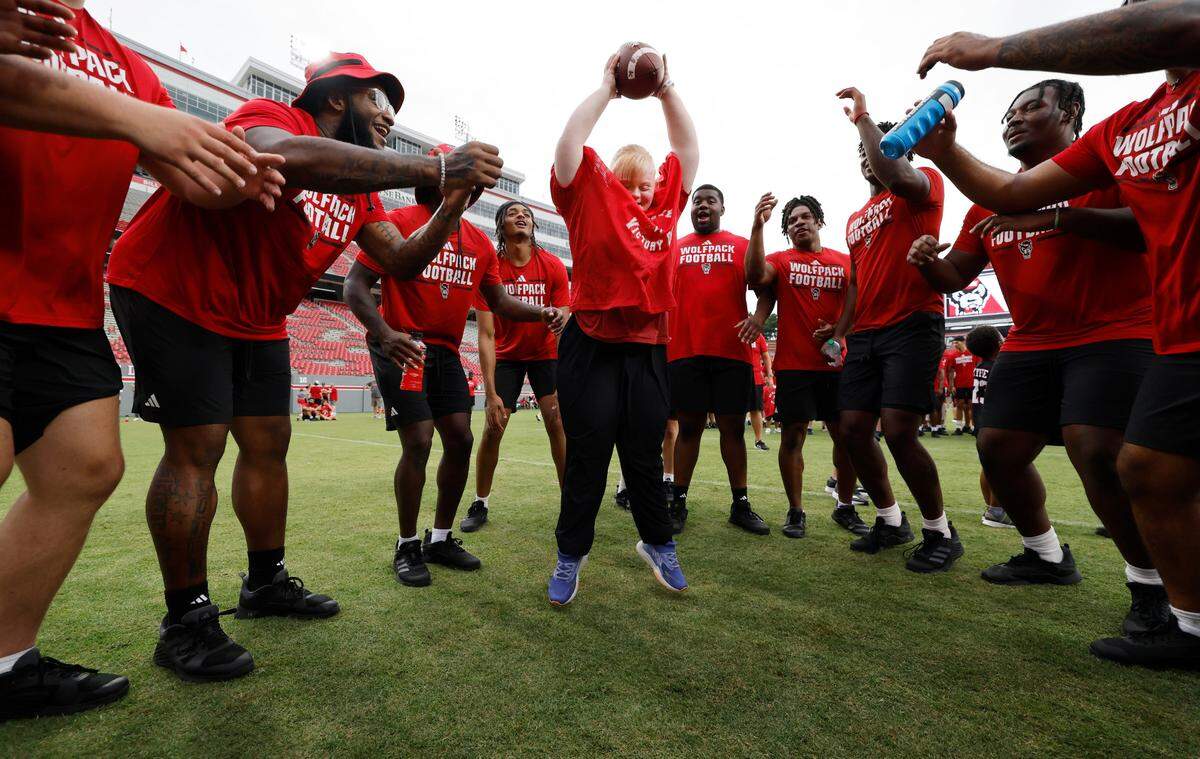 Jennifer Zizzi celebrates scoring a touchdown with N.C. State football players during Victory Day at Carter-Finley Stadium in Raleigh, N.C., Friday, August 2, 2024. Victory Day is a partnership between the Wolfpack and GiGi’s Playhouse, a Down Syndrome achievement center in Raleigh. The event provided 52 cognitively and physically impaired people the chance to be football stars for the night. They tried on uniforms, met the players and coaches, ran through the tunnel and competed in drills with the players.