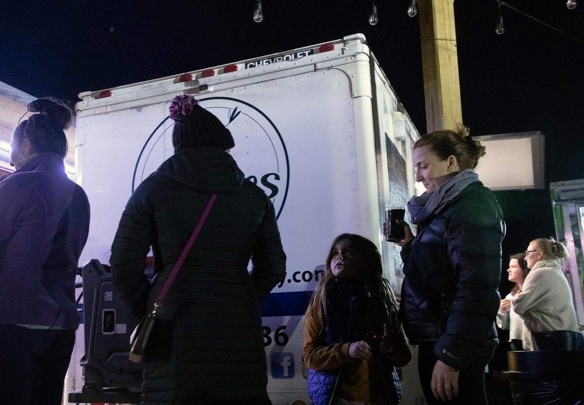 Elowyn Hoelscher, 7, stands in line at a food truck with her mother, Erika Hoelscher, at Red’s Corner during the Moore County power outage on Monday, Dec. 5, 2022, in Southern Pines, N.C.