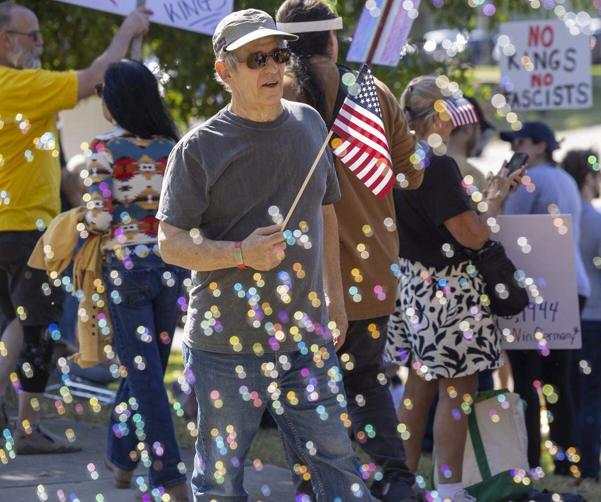 Jim Goodman of Raleigh, N.C., walks through a sea of  bubbles during the ‘No Kings’ demonstration along Capital Blvd. on Saturday, October 18, 2025 in Raleigh, N.C.