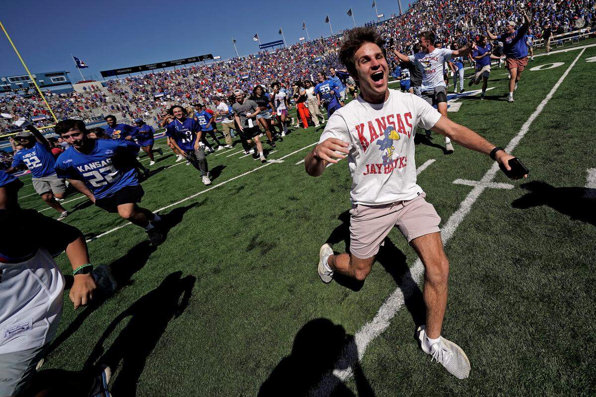 Fans celebrate on the field after an NCAA college football game between Kansas and Duke Saturday, Sept. 24, 2022, in Lawrence, Kan. Kansas won 35-27.