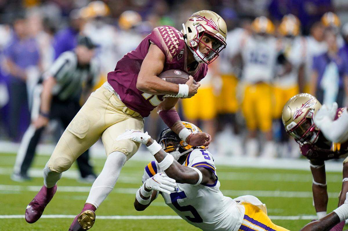 Florida State quarterback Jordan Travis (13) tries to avoid LSU safety Jay Ward (5) during their game in New Orleans on Sept. 4, 2022.