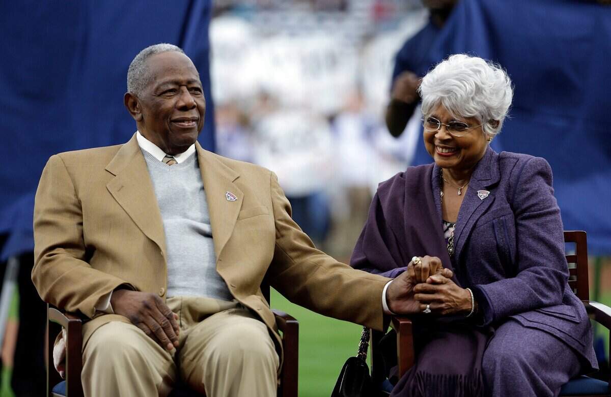 In this April 8, 2014, file photo, Hank Aaron, left, sits with his wife Billye, during a ceremony celebrating the 40th anniversary of his 715th home run before the start of a baseball game between the Atlanta Braves and the New York Mets in Atlanta. Hank Aaron, who endured racist threats with stoic dignity during his pursuit of Babe Ruth but went on to break the career home run record in the pre-steroids era, died early Friday, Jan. 22, 2021. He was 86. The Atlanta Braves said Aaron died peacefully in his sleep. No cause of death was given.