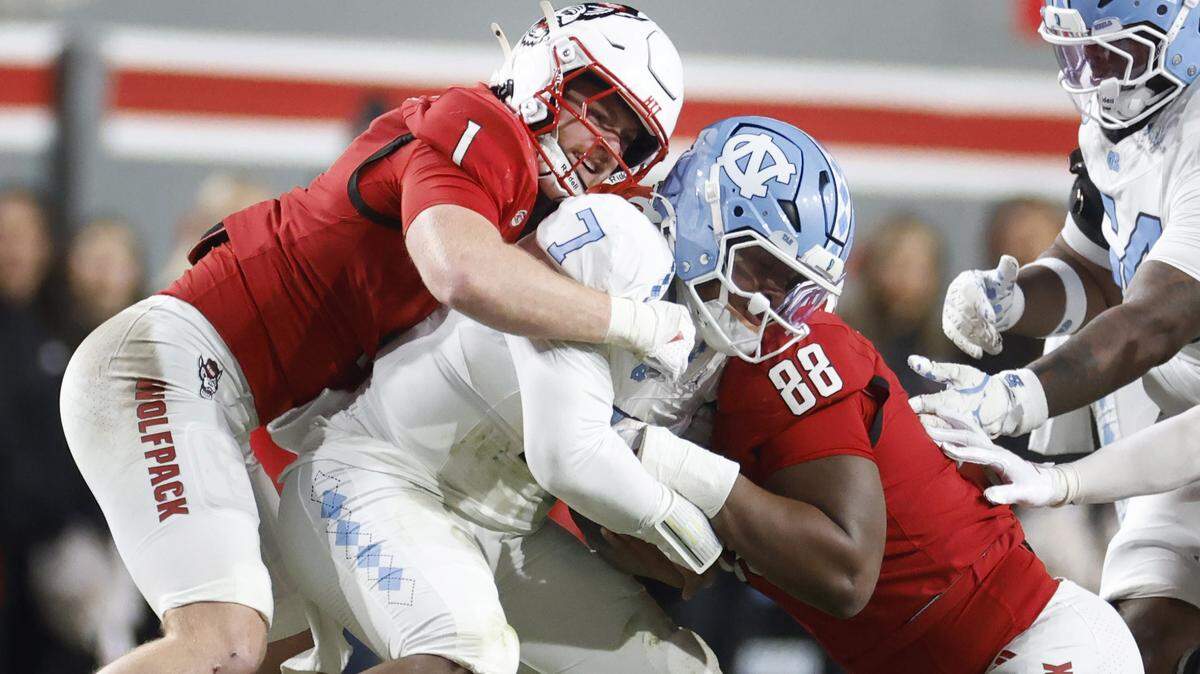 N.C. State linebacker Caden Fordham (1) and defensive end Isaiah Shirley (88) sack North Carolina quarterback Gio Lopez (7) during the first half of N.C. State’s game against UNC at Carter-Finley Stadium in Raleigh, N.C., Saturday, Nov. 29, 2025.