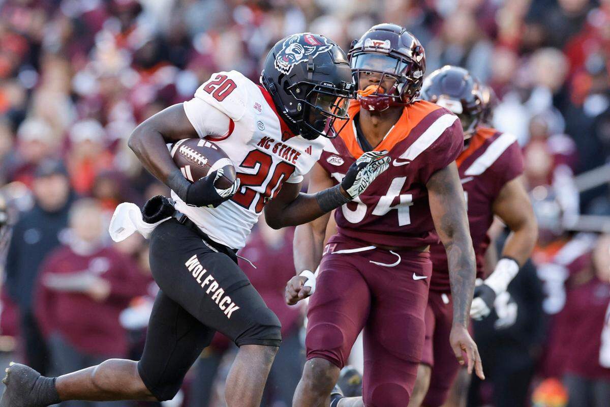 N.C. State running back Kendrick Raphael (20) gains yards as Virginia Tech linebacker Alan Tisdale (34) closes in during the first half of N.C. State’s game against Virginia Tech at Lane Stadium in Blacksburg, VA, Saturday, Nov. 18, 2023.