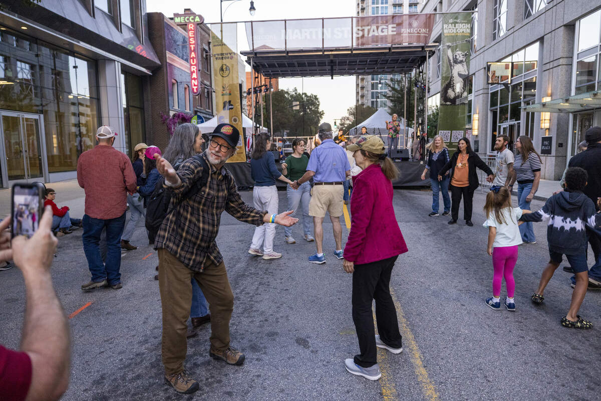 Festival-goers square dance on Martin Street during the Raleigh Wide Open music festival in downtown Raleigh on Friday, Oct. 3, 2025. The event features live bluegrass, folk, Americana and gospel artists.