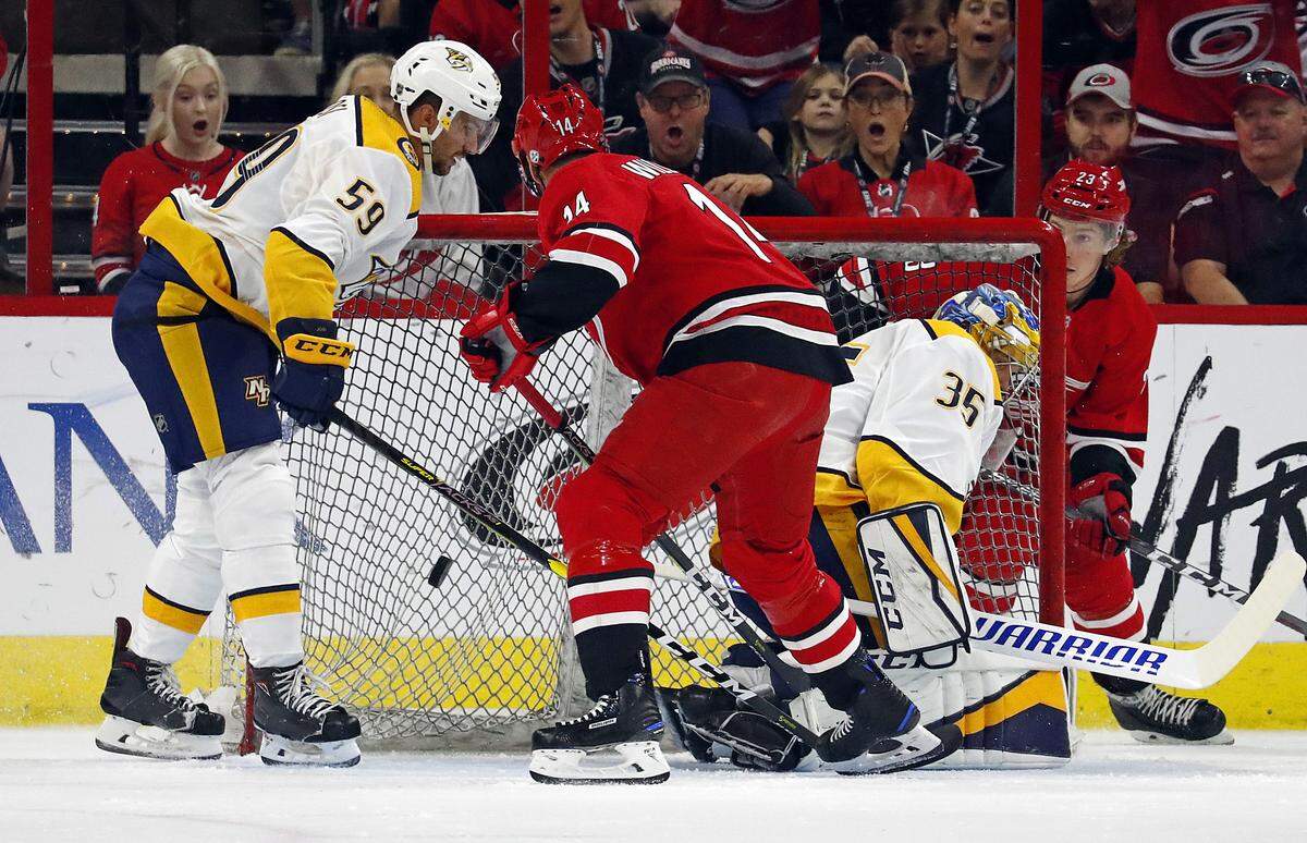 Carolina Hurricanes’ Justin Williams (14) slips the puck between Nashville Predators’ Roman Josi (59) and goaltender Pekka Rinne (35) for a goal during the first period of an NHL hockey game, Sunday, Sept. 30, 2018, in Raleigh, N.C. 