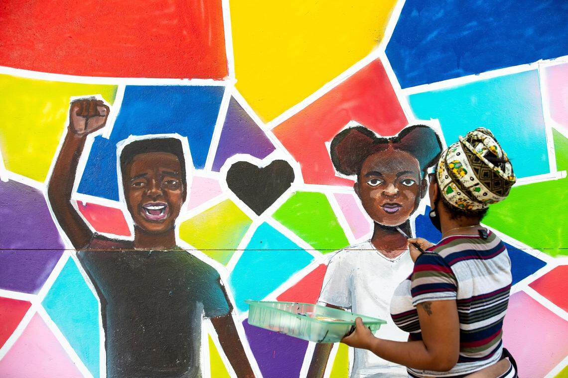 Kiara Sanders works on a mural in Downtown Durham, N.C. on Sunday, June 7, 2020. Artists have come to downtown Durham to paint murals on plywood boarded-up businesses after protests against the death of George Floyd, who was killed by a Minneapolis police officer, have come to Durham and many cities across the country.