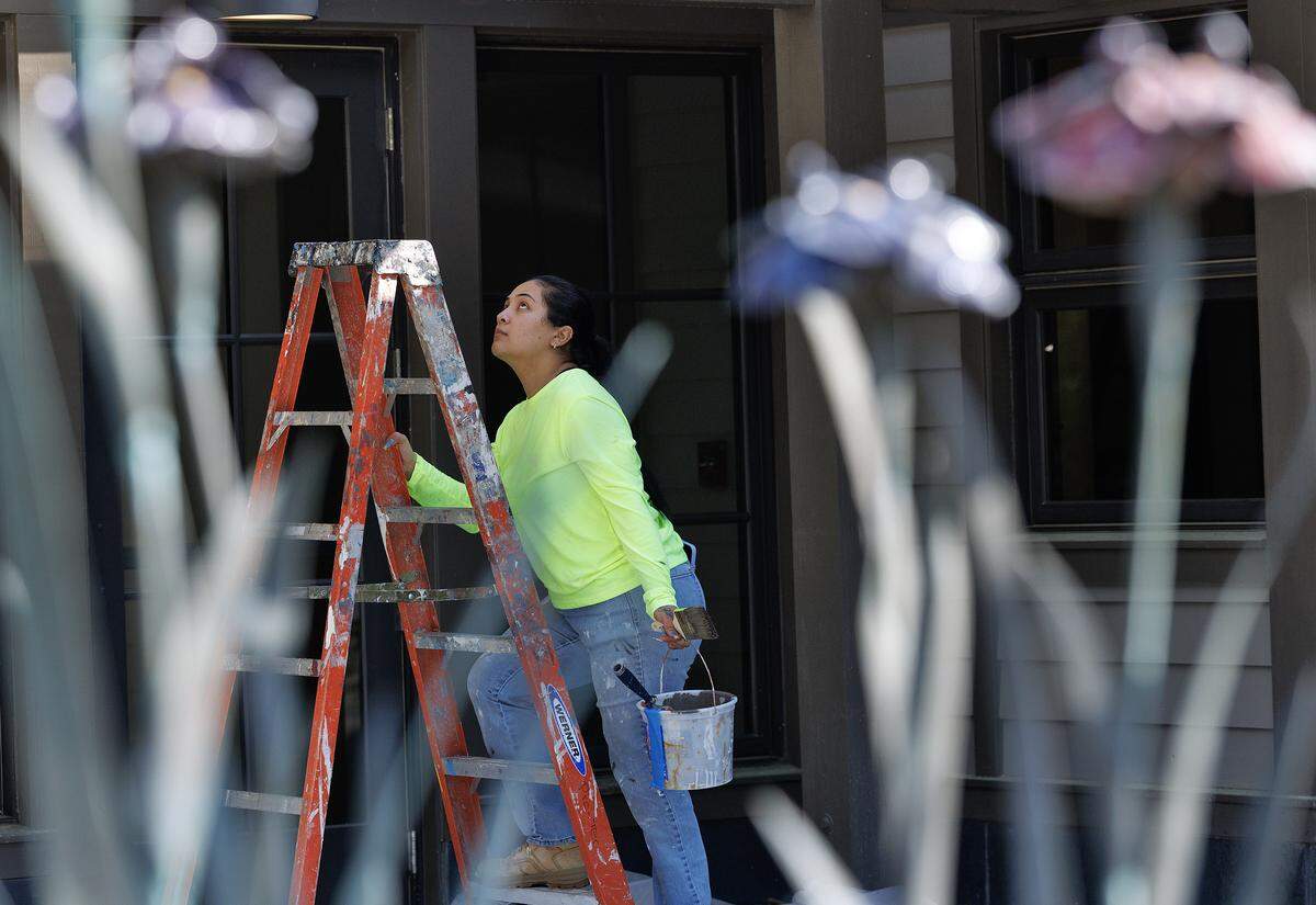 Genesis Duron is framed by the Iris Fountain while painting the exterior of the Doris Duke Center at Sarah P. Duke Gardens on Thursday, April 2, 2026, in Durham, N.C. The newly renovated Doris Duke Center includes a bigger indoor event space, an expanded catering kitchen and an outdoor patio. 