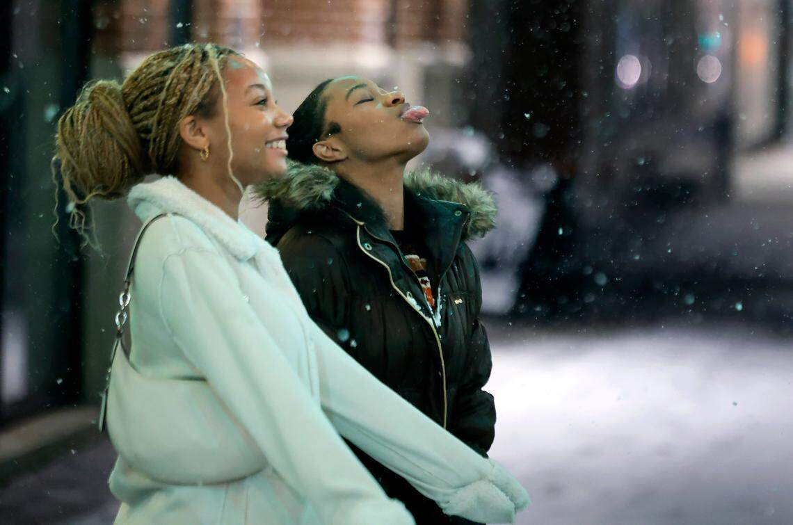 Doey Heard, right, and Sanaa Dunston enjoy the snow falling while standing on Fayetteville Street in downtown Raleigh, N.C., Tuesday evening, Jan. 21, 2025.
