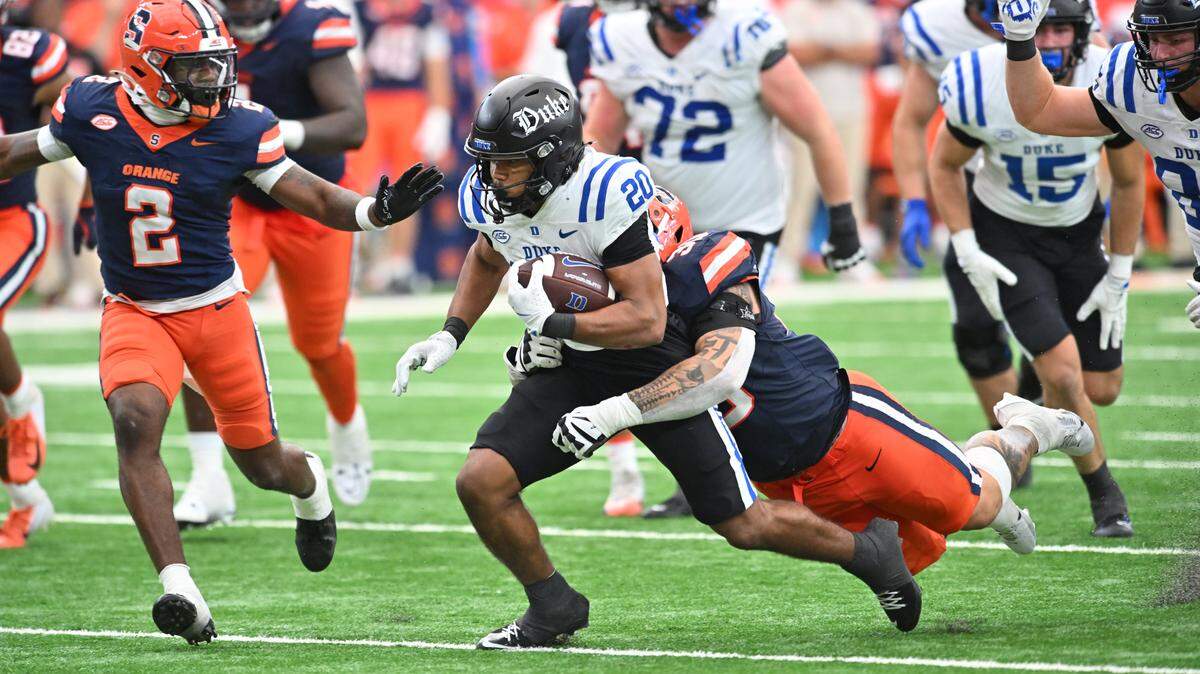 Sep 27, 2025; Syracuse, New York, USA; Duke Blue Devils running back Nate Sheppard (20) is tackled by Syracuse Orange defensive lineman Nathan Nyandoro (30) and defensive back Duce Chestnut (2) in the fourth quarter at the JMA Wireless Dome. Mandatory Credit: Mark Konezny-Imagn Images