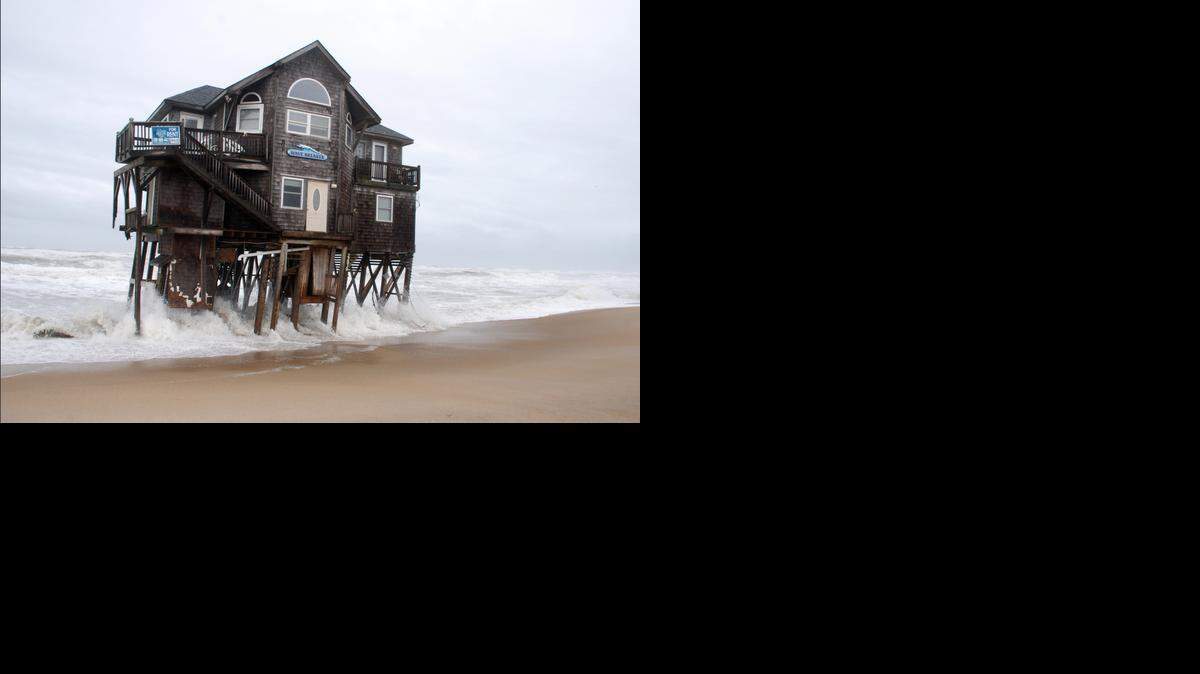 An incoming tide amplified by a two-day nor’easter undermines a cottage named WAVE BREAKER in the fast-eroding Mirlo Beach section of Rodanthe on Hatteras Island, on March 7, 2014. 
