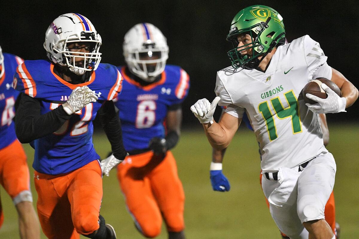 Cardinal Gibbons’ Chey Yardley (14) runs for the first down against Athens Drive’s Izaiah Lucas (32) in the first half. The Cardinal Gibbons Crusaders and the Athens Drive Jaguars met in a conference football game in Raleigh , N.C. on September 29, 2023.