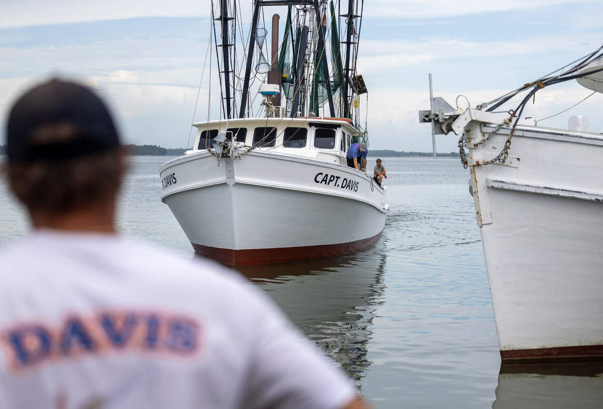 Jody Davis waits at the dock, outside the fish house he co-owns, to unload brown shrimp caught by a crew captained by his older brother Billy Davis.
