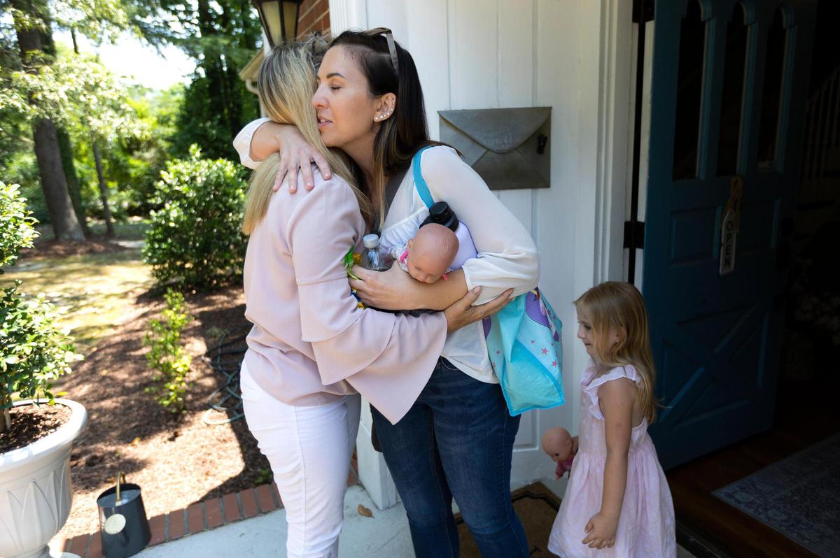 Katie Shaw gives Tonya Baker Nelson a hug after participating in an interview at the Hand of Hope Pregnancy Center in Fuquay-Varina. At right is Shaw’s daughter, Gemma, 3,