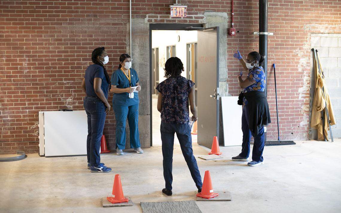 Advance Community Health employees listen to Andrea Thompson, right, as they set up their facility to screen for the COVID-19 virus and address other health issues for the homeless and displaced population at Oak City Cares on S. Wilmington Street on Tuesday, April 7, 2020 in Raleigh, N.C.