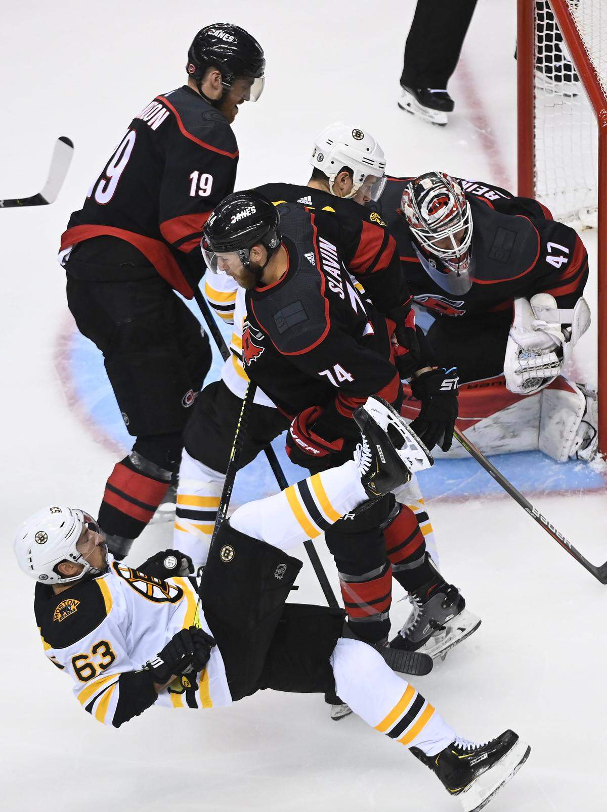 Boston Bruins left wing Brad Marchand (63) gets knocked to the ice by Carolina Hurricanes defenceman Jaccob Slavin (74) after the whistle during the first period of an NHL Eastern Conference Stanley Cup playoff game, in Toronto, Ontario, Monday, Aug. 17, 2020. (Nathan Denette/The Canadian Press via AP)